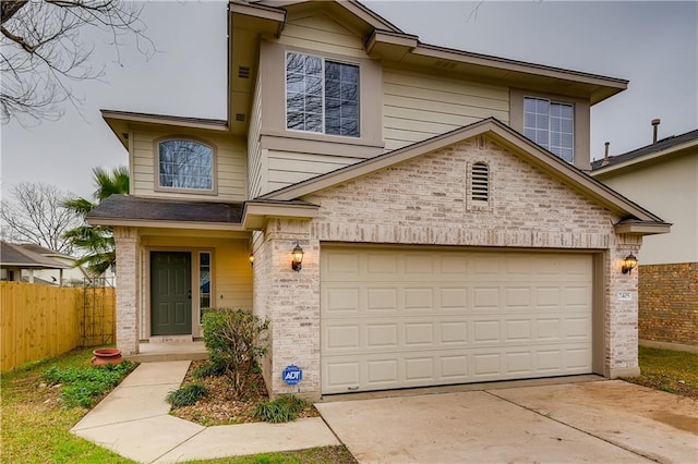 traditional-style house with brick siding, an attached garage, concrete driveway, and fence