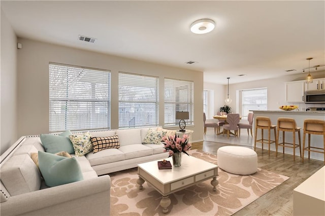 living area featuring visible vents, baseboards, and light wood-style floors