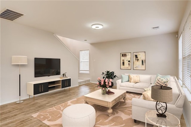 living room featuring visible vents, baseboards, and wood finished floors