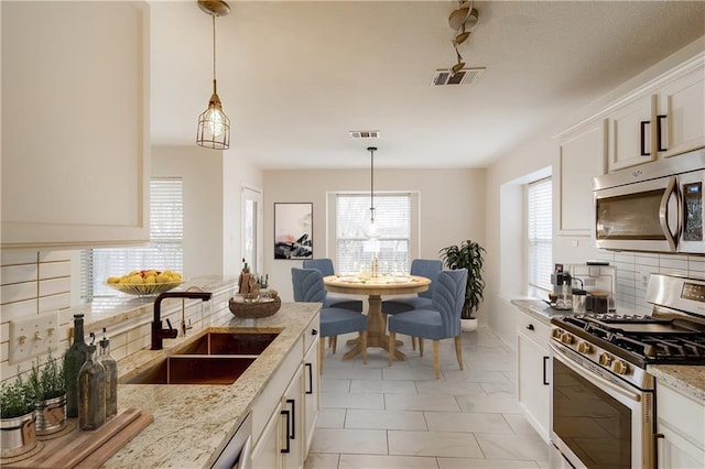 kitchen with light stone counters, visible vents, stainless steel appliances, and a sink