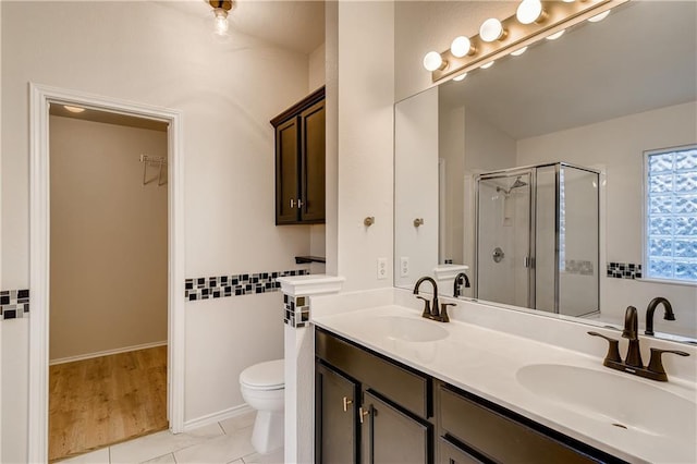 full bathroom featuring double vanity, toilet, a stall shower, and a sink