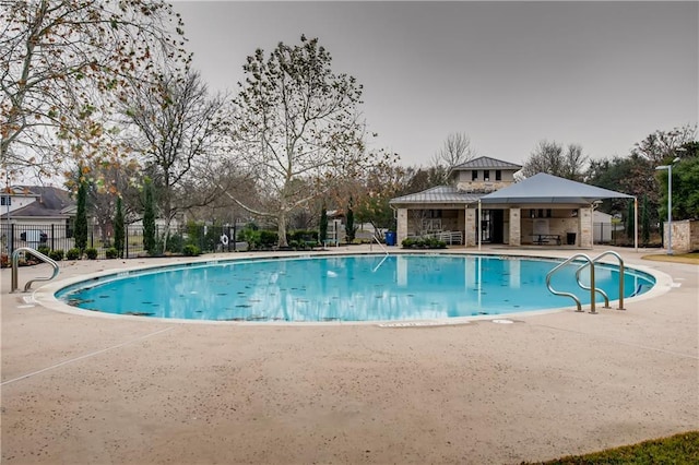 community pool with a patio and fence