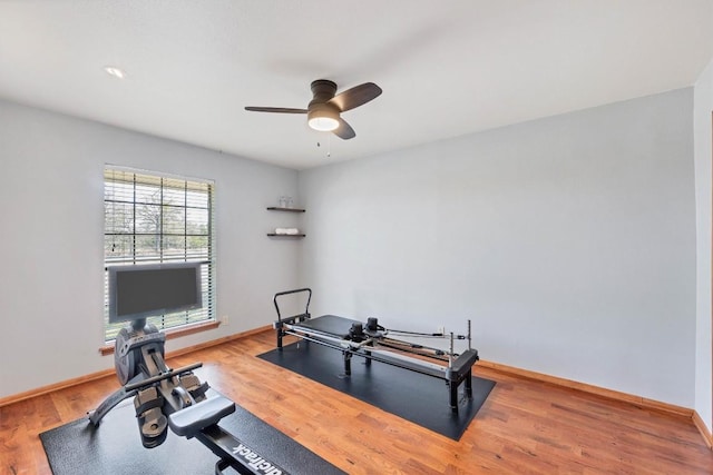 workout room with a ceiling fan, wood finished floors, and baseboards