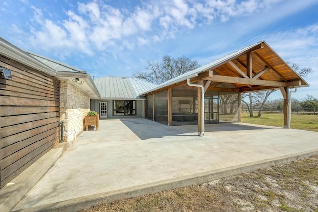 view of patio with a detached carport, concrete driveway, and a sunroom