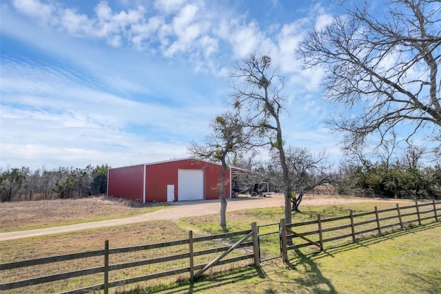 view of yard with an outbuilding, dirt driveway, and fence