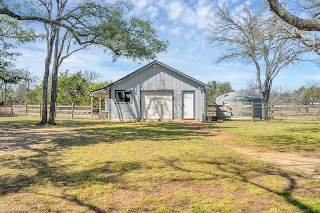 view of pole building with driveway, a yard, and fence