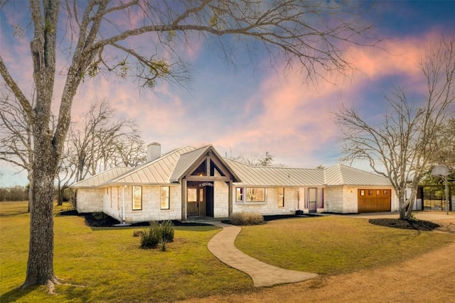 view of front of home featuring a front yard, a standing seam roof, a chimney, stone siding, and metal roof