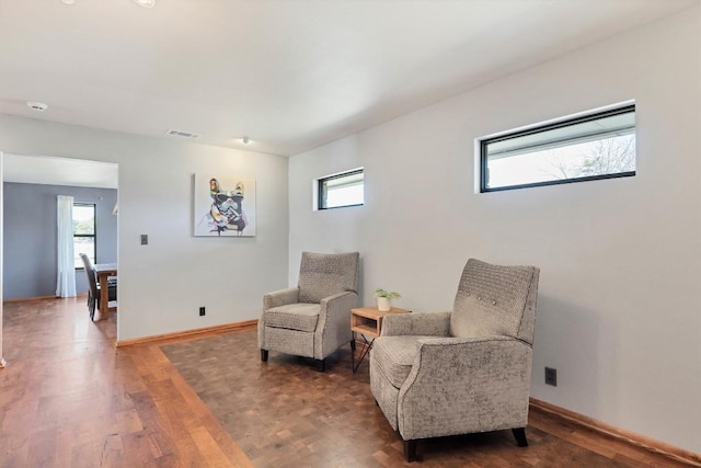 living area featuring visible vents, a healthy amount of sunlight, baseboards, and wood finished floors