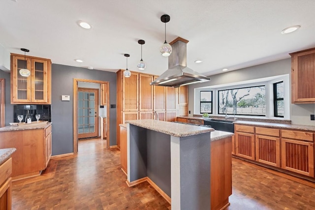 kitchen with hanging light fixtures, recessed lighting, island exhaust hood, and a sink