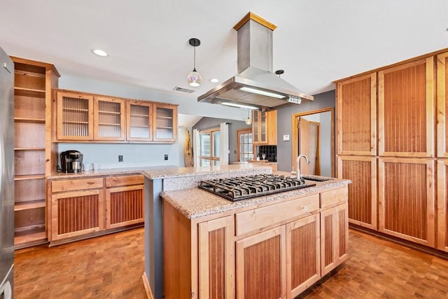 kitchen featuring visible vents, a kitchen island, stainless steel gas cooktop, island exhaust hood, and a sink