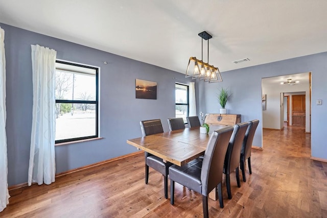 dining area featuring a notable chandelier, visible vents, light wood-type flooring, and baseboards