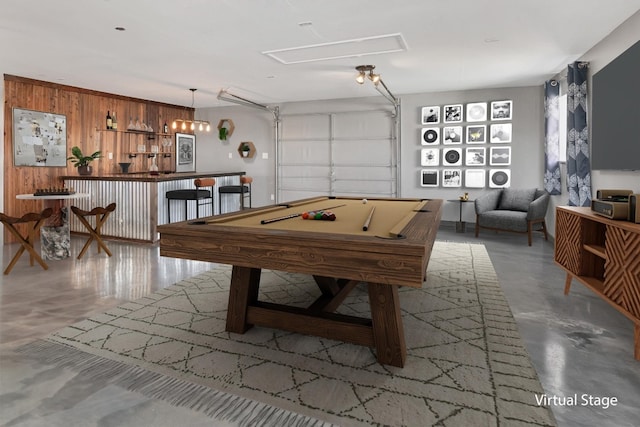 recreation room with wood walls, pool table, concrete flooring, and a garage