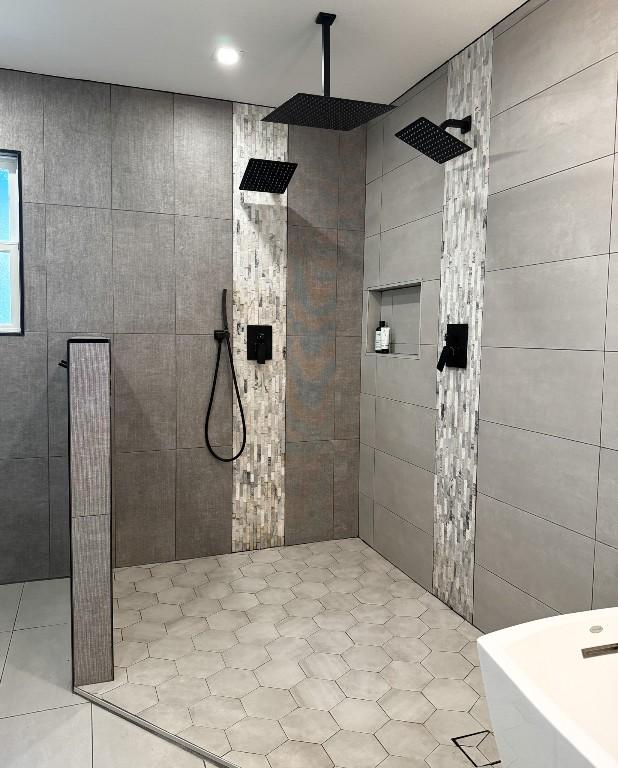 full bath featuring a tile shower, a freestanding bath, and tile walls