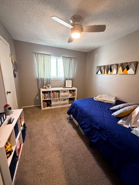 carpeted bedroom featuring ceiling fan and a textured ceiling