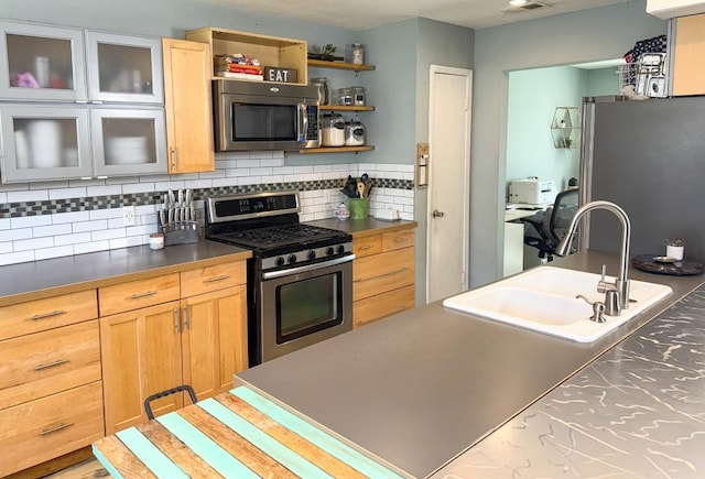kitchen featuring dark countertops, visible vents, decorative backsplash, stainless steel appliances, and a sink