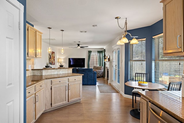 kitchen with light brown cabinets, open floor plan, pendant lighting, a peninsula, and wood finished floors