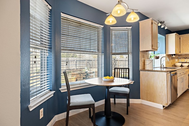 kitchen featuring light brown cabinets, dishwasher, light wood-type flooring, decorative backsplash, and a sink