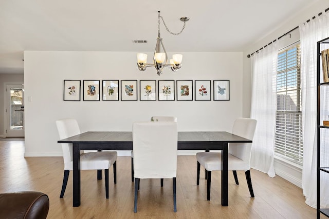 dining area with light wood-style flooring, baseboards, visible vents, and a chandelier