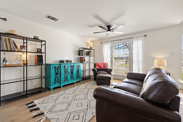 living room featuring visible vents, ceiling fan, and wood finished floors