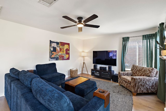 living area featuring visible vents, baseboards, wood finished floors, and a ceiling fan