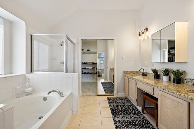 bathroom featuring a shower stall, a walk in closet, vaulted ceiling, tile patterned floors, and a sink