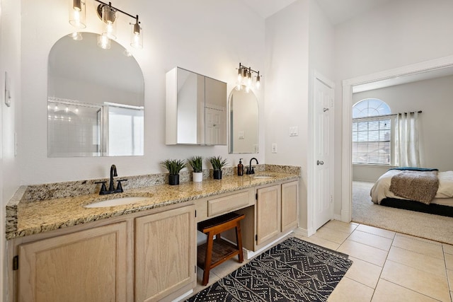 ensuite bathroom featuring a sink, a shower with shower door, double vanity, and tile patterned floors