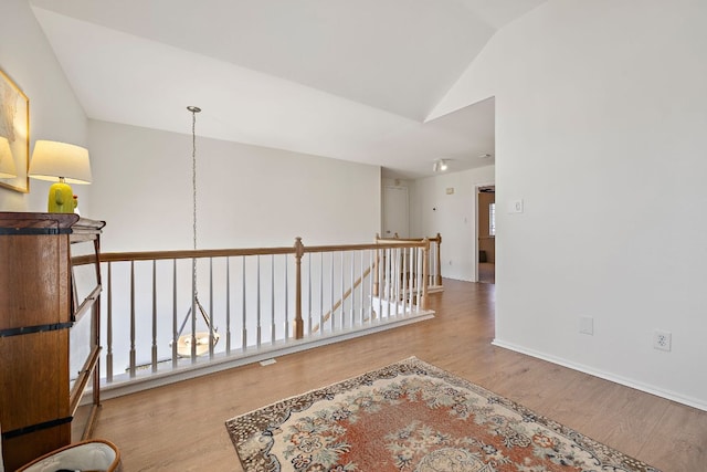 interior space with baseboards, an upstairs landing, wood finished floors, and vaulted ceiling