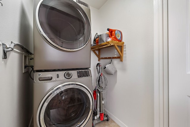 clothes washing area with laundry area, baseboards, stacked washer / drying machine, and tile patterned floors