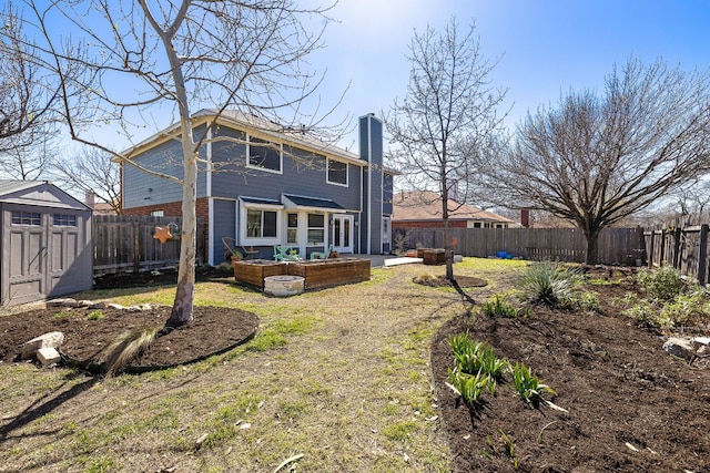 back of house featuring a shed, a chimney, and a fenced backyard