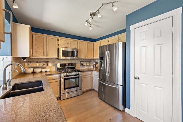 kitchen with light wood finished floors, tasteful backsplash, light brown cabinetry, stainless steel appliances, and a sink