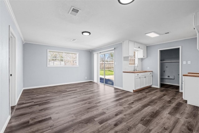 unfurnished living room featuring a sink, visible vents, dark wood finished floors, and ornamental molding