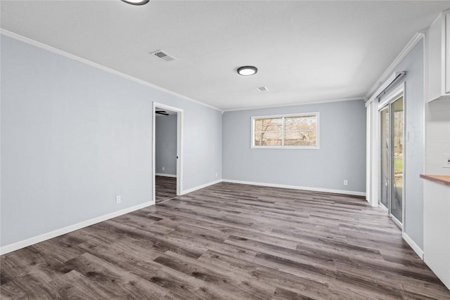 spare room featuring wood finished floors, baseboards, and ornamental molding