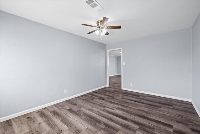 spare room with visible vents, ceiling fan, dark wood-type flooring, and baseboards