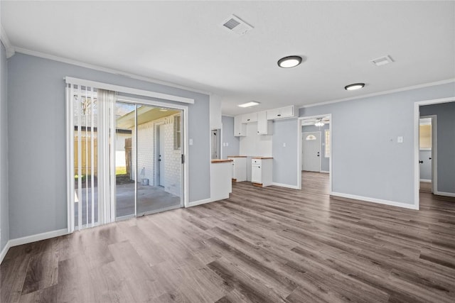 unfurnished living room with visible vents, wood finished floors, and crown molding