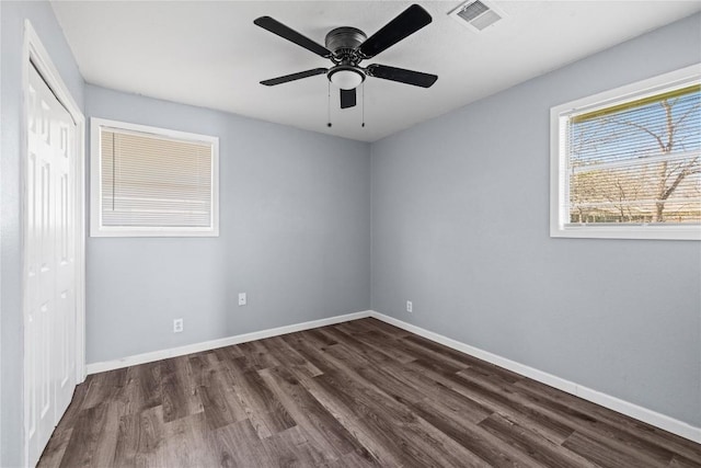 unfurnished bedroom with visible vents, ceiling fan, baseboards, a closet, and dark wood-style flooring