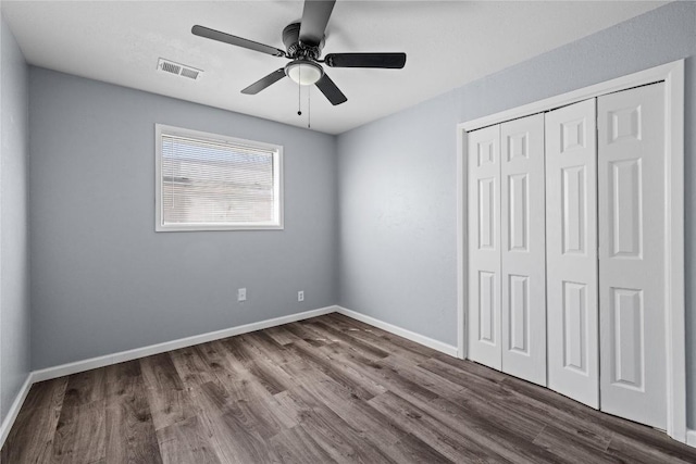 unfurnished bedroom featuring a closet, visible vents, dark wood-type flooring, and baseboards