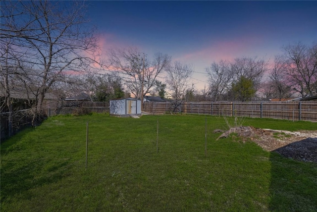 view of yard with a storage unit, an outbuilding, and a fenced backyard