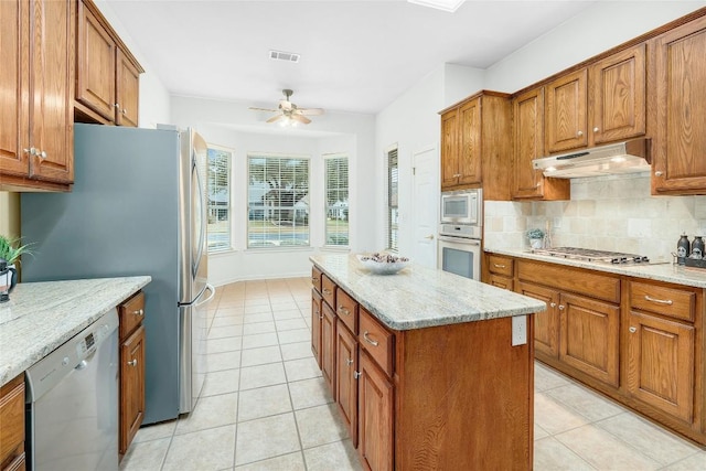 kitchen featuring brown cabinets, visible vents, under cabinet range hood, and stainless steel appliances