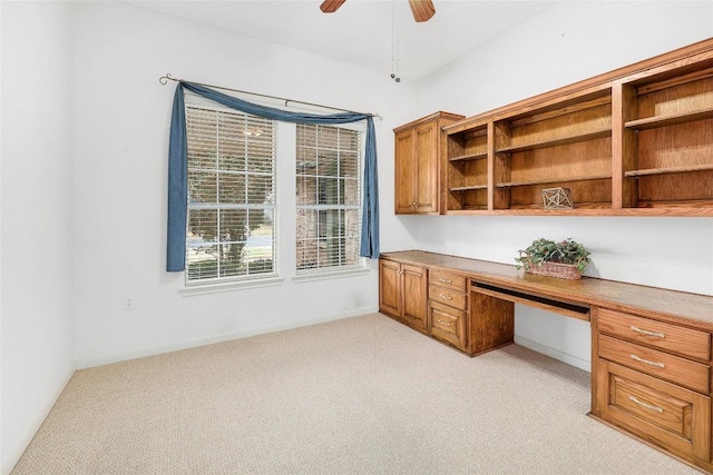 unfurnished office with ceiling fan, light colored carpet, and built in study area