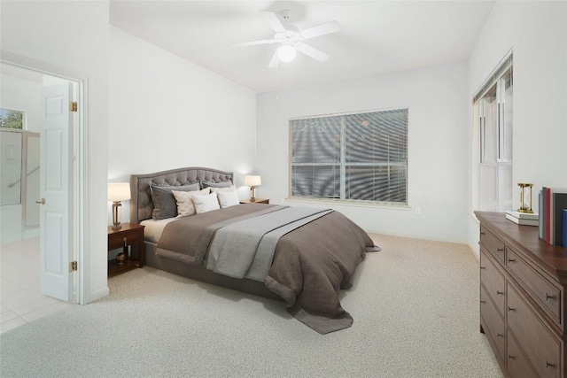 carpeted bedroom with ensuite bath and a ceiling fan