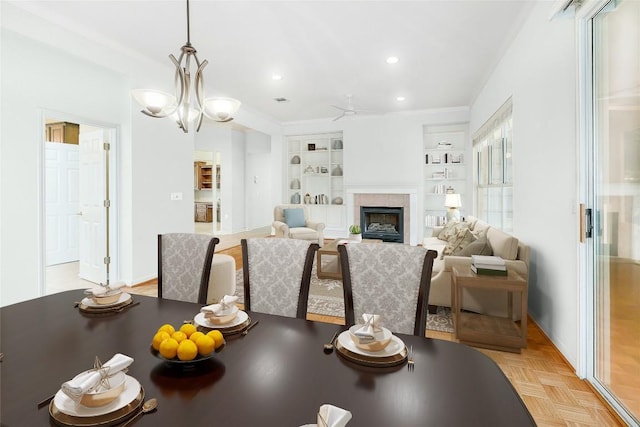 dining space featuring built in shelves, a fireplace, recessed lighting, ornamental molding, and ceiling fan with notable chandelier