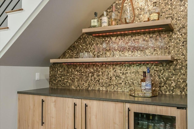 bar with backsplash, a bar, and beverage cooler