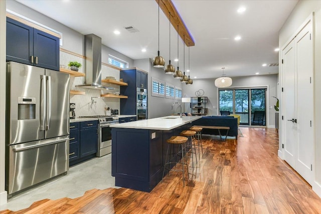 kitchen featuring blue cabinets, visible vents, a sink, ventilation hood, and stainless steel appliances