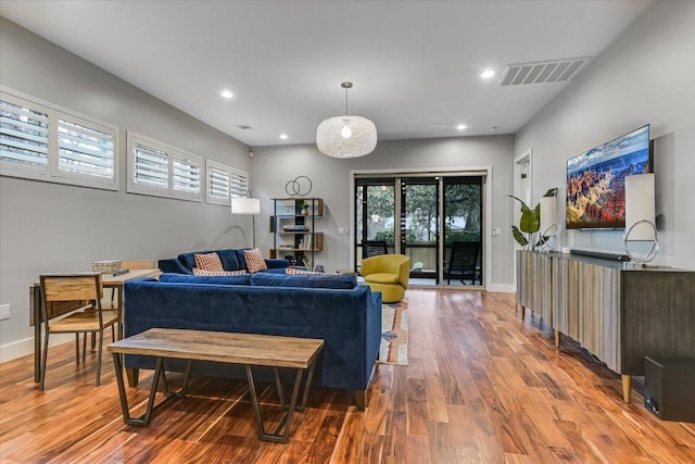 living area with recessed lighting, wood finished floors, visible vents, and baseboards