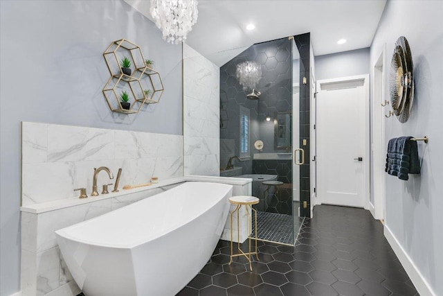 bathroom featuring tile patterned floors, a freestanding tub, tile walls, a shower stall, and a chandelier