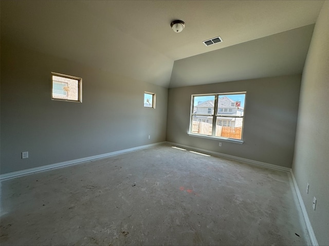 spare room featuring visible vents, lofted ceiling, concrete flooring, and baseboards