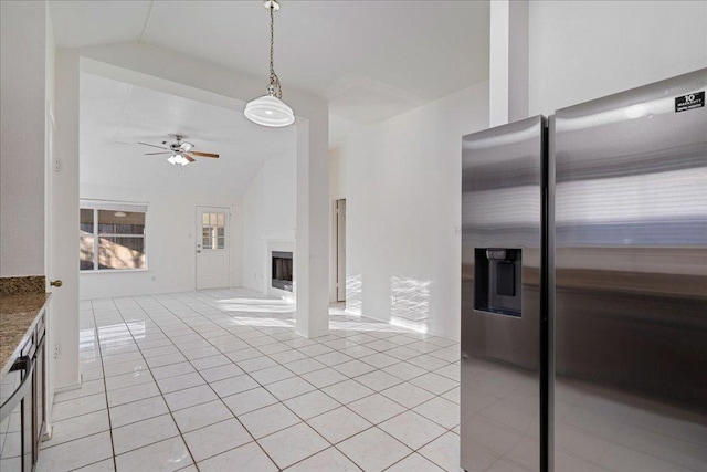 kitchen with light tile patterned floors, a ceiling fan, lofted ceiling, a fireplace, and stainless steel refrigerator with ice dispenser