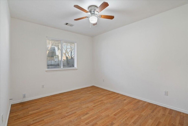 spare room with baseboards, light wood-style floors, visible vents, and ceiling fan