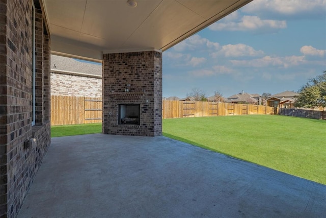 view of patio / terrace with a fenced backyard and an outdoor brick fireplace