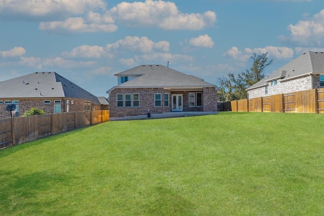 rear view of property with a yard, a fenced backyard, and brick siding